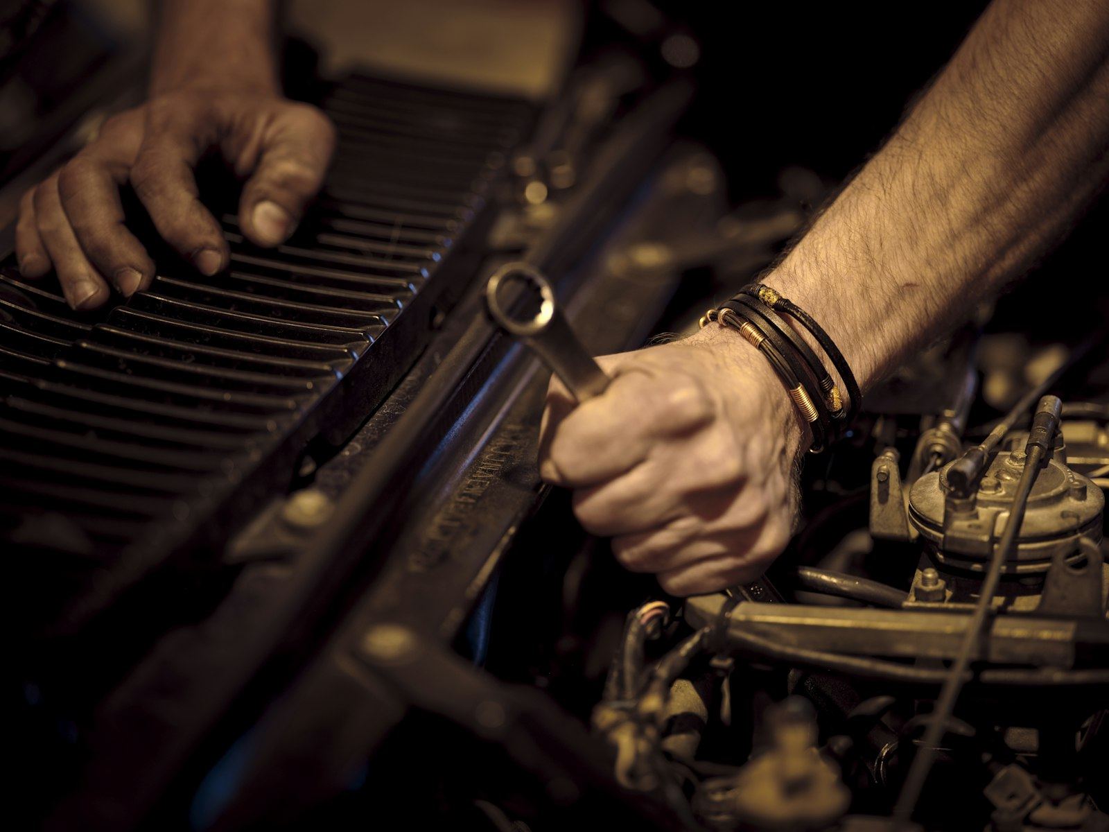 Mechanic's hands working with a wrench in an engine bay
